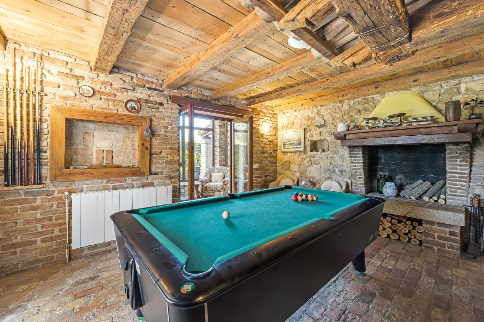 Der Billardraum mit Pooltisch unter der Holzbalkendecke