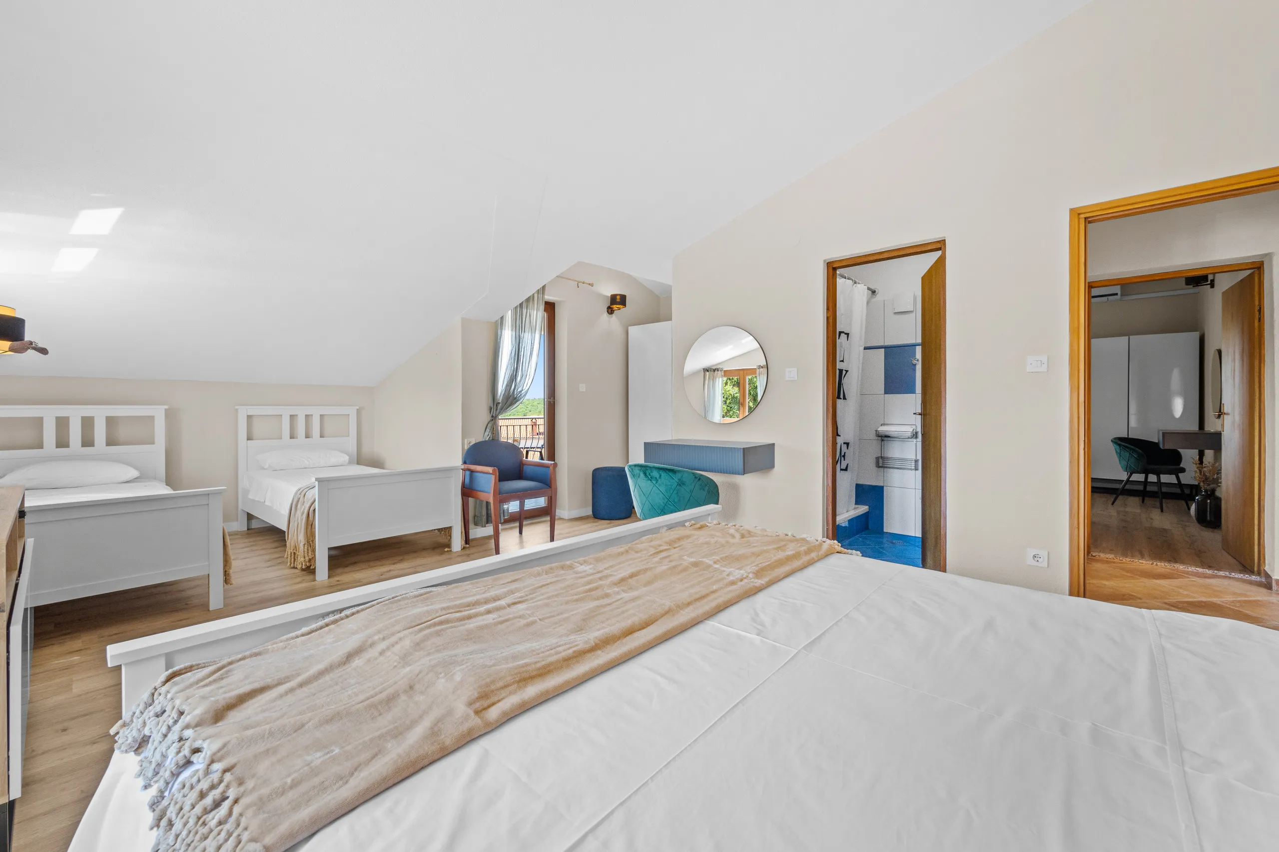 Ein Zimmer auf zwei Ebenen, unten ein Doppelbett, oben zwei Einzelbetten und ein gefliestes Duschbad
